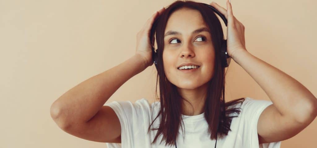 Dreamy young woman listening to music in headphones