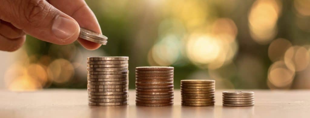 Human Hands Holding Coins and Piles of Coins on Wooden Floor Financial