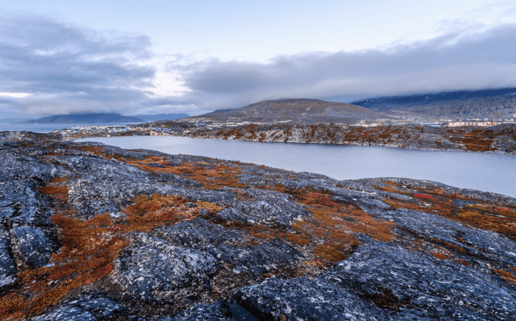 Autumn Greenlandic orange tundra landscape with lake and mountains