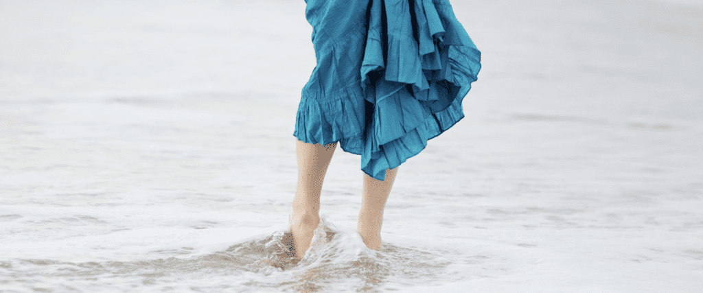Ocean waves wash young womans feet