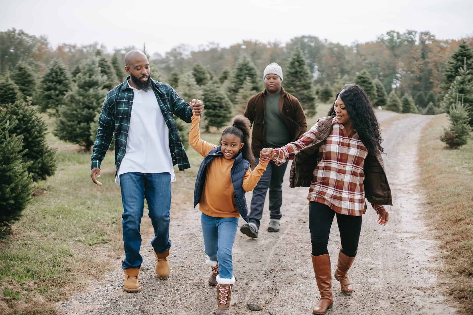 How To Budget For Holiday Spending In An Economic Downturn 4 smiling ethnic family walking on tree farm road