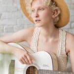 gorgeous young lady playing classic guitar and looking away pensively