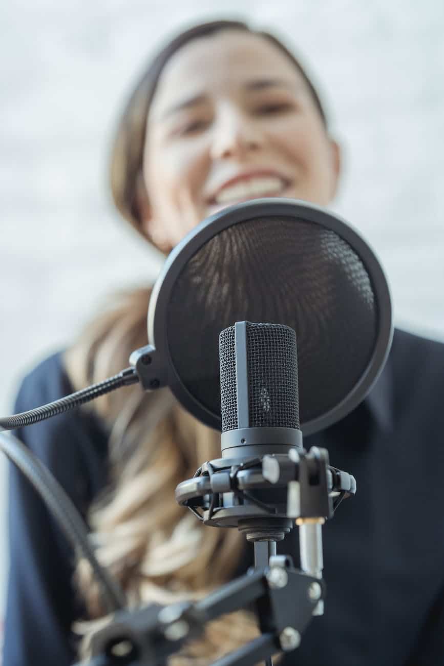 positive woman smiling and recording audio message with microphone
